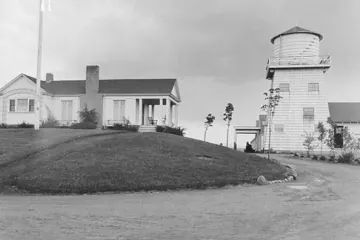 The demonstration farm's white cottage and wooden water tower, about 1925.