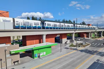 A light-rail train on the elevated guideway at Mountlake Terrace station under a blue sky.