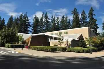 The Hibulb Cultural Center of the Tulalip Tribes, a low building with a sloping roof among tall firs.